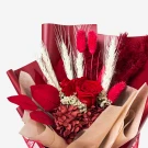 A red preserved rose bouquet with dried wheat, red caspia, and red hydrangeas.