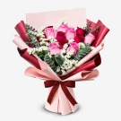 Bouquet of red and pink roses with white statice and eucalyptus, wrapped in pink and red paper with a burgundy bow.