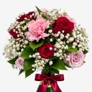 A bouquet of red roses, pink carnations, and baby's breath tied with a burgundy ribbon, with the neck of a green bottle visible.
