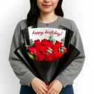 A bouquet of 12 red roses wrapped in black paper with a "happy birthday!" card.