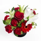 Round box of red and white flowers: red roses, carnations, gerberas, and lilies.