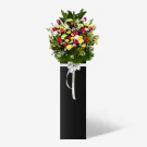 Floral sympathy stand with white lilies, pink roses, yellow and white carnations, yellow mums, and white matthiola.