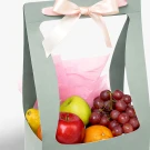 Gift basket with grapes, apples, orange, and lemon, tied with a pink bow.