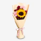Sunflower and pink carnations bouquet, wrapped in beige paper and tied with a pink ribbon.