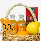 Wicker basket with orange juice, lemon, oranges, tea, and mini straws.
