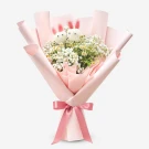 Bouquet of white chamomile and baby's breath flowers with two bunny decorations, wrapped in pink paper and tied with a pink ribbon.