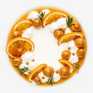 Round chocolate caramel cake with orange slices, meringue, and rosemary.