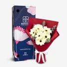 White gerberas and eucalyptus bouquet next to a blue gift box with floral design.