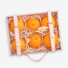 Gift box with 6 oranges, pink ribbon, and shredded paper.