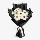 Bouquet of white gerberas with eucalyptus, wrapped in black paper and tied with a cream ribbon.
