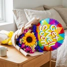 Sunflower bouquet with purple flowers and a "Get Well Soon" balloon on a bedside table.