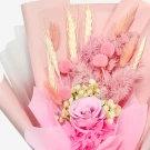 A delicate pink rose bouquet with dried wheat and pink filler flowers, wrapped in pink paper.