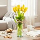 Yellow tulips in a clear vase tied with twine, placed on a coffee table with cookies and a book.