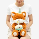A plush fox wearing a party hat holds a cupcake with a candle.
