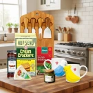 Gift set with cheese board, crackers, brie, jam, tea, and bird mugs.