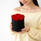 Woman holding a black box with preserved red roses.