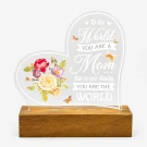 Heart-shaped acrylic lamp with floral design and "To the World You Are a Mom, But to Our Family You Are the World" message on wooden base.