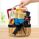 A wicker gift basket filled with chocolates, shortbread, coffee, cocoa, and sparkling grape juice.