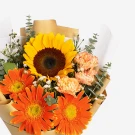 Sunflower, orange gerbera daisies, and pink carnations in a rustic brown paper wrap.