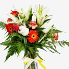 A vibrant bouquet of white lilies, orange gerbera daisies, red carnations, and white roses with green fern accents.
