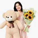 Woman holding a giant teddy bear and a bouquet of sunflowers.