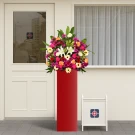 Grand red floral stand with white lilies, red and white roses, gerberas, carnations, mums, and greenery.