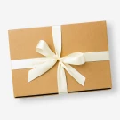 Brown gift box with cream ribbon tied in a bow, on a white background.