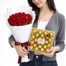 Woman holding a bouquet of red roses and a box of Ferrero Rocher chocolates.