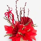 Red pussy willow branches, red fans, and gold eucalyptus leaves in a woven basket.