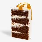 Slice of chocolate cake with white frosting, caramel drizzle, and orange slices.