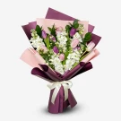 Bouquet of purple and pink tulips with white flowers and green leaves, wrapped in pink and purple paper with a white ribbon.