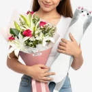 Woman holding a bouquet of white lilies and pink roses, and a gray cat plushie.