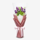 Bouquet of seven purple tulips with sparkly bands, wrapped in pink paper with a pink ribbon.