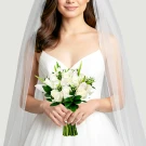 Bride holding a white rose and calla lily bouquet under a veil.