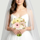 Bride in a white dress holding a bouquet of pink, yellow, and white flowers under a sheer veil.