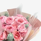 Bouquet of pink spray roses with eucalyptus, wrapped in soft pink paper.