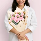 Woman holding a bouquet of pink carnations and eucalyptus.