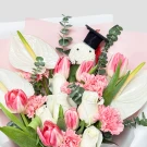 Bouquet with white anthuriums, pink and white tulips, pink carnations, and a graduation charm.
