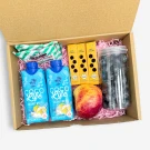 Cardboard box with coconut water, mint lozenges, mini straws, blueberries, and an apple.