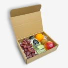 Cardboard gift box with grapes, orange, kiwi, red apple, and bottle of Vida lime water.