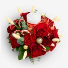 Christmas floral arrangement with red roses, carnations, candy canes, ornaments, and a white candle.