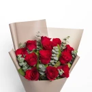 A bouquet of 12 red roses with eucalyptus in beige paper wrapping.