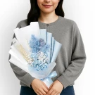 Woman holding a blue and white preserved flower bouquet with wheat stalks.