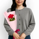Woman holding a single red carnation in pink wrapper.