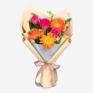 A bouquet of bright orange and pink gerbera daisies and roses, wrapped in pale beige paper and tied with a pink ribbon.