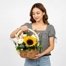 Easter basket with sunflowers and bunny decorations, held by a person's hand.