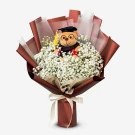 Graduation teddy bear in a bouquet of baby's breath with brown paper and ribbon.