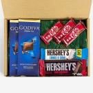 Gift box with Godiva, KitKat, and Hershey's chocolates on a green fabric.