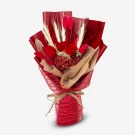 Red dried flowers in a bouquet with wheat stalks and red accents, wrapped in red paper and mesh with twine.