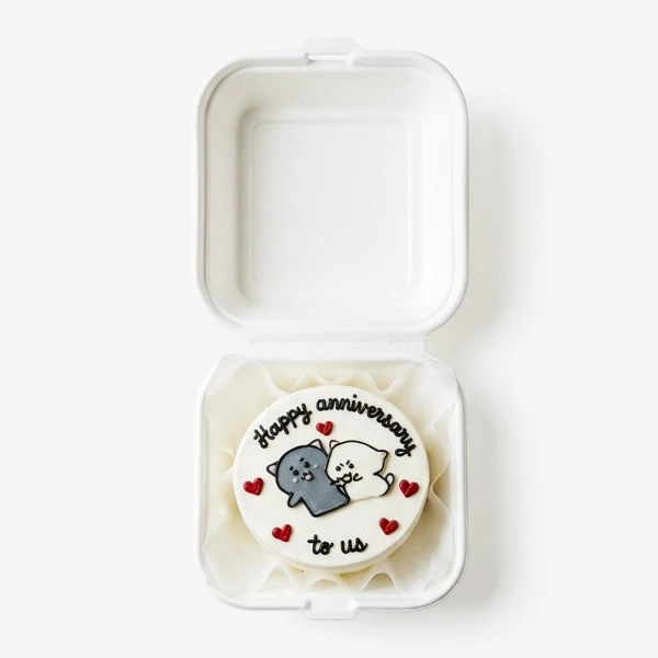 Anniversary cake with two cats, hearts, and text "Happy anniversary to us" in a white box.